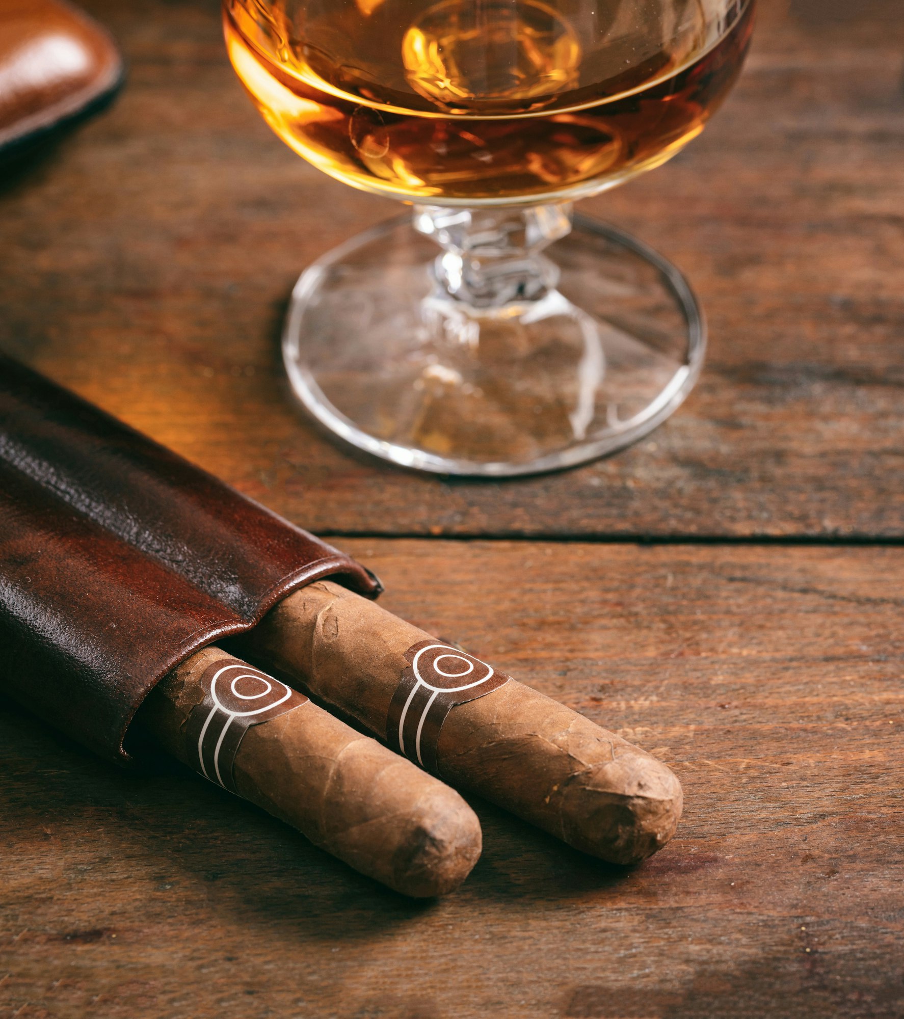 Cuban cigars and snifter with rum on wooden table